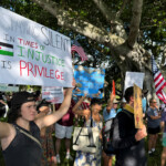 Protesters hold signs as they take part in a "No Kings" protest against U.S. President Donald Trump's presidency and immigration policies, near Mar-a-Lago, in West Palm Beach, Florida, U.S., June 14, 2025. REUTERS/Julien Pretot