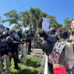 Protesters hold signs and face police during a "No Kings" protest against U.S. President Donald Trump's presidency and immigration policies, near Mar-a-Lago, in West Palm Beach, Florida, U.S., June 14, 2025. REUTERS/Julien Pretot