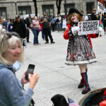 A person wearing a costume holds placards during the "No Kings" rally, in Chicago, Illinois, U.S., June 14, 2025. REUTERS/Dylan Martinez