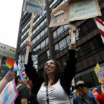 A woman holds placards as people convene for the start of the "No Kings" rally at the Daley Plaza in downtown Chicago, Illinois, U.S., June 14, 2025. REUTERS/Octavio Jones