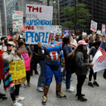 Adam Held, wearing a Captain America costume, holds a placard as people convene for the start of the "No Kings" rally at the Daley Plaza in downtown Chicago, Illinois, U.S., June 14, 2025. REUTERS/Octavio Jones