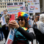 A woman holds a phone as people gather to attend the "No Kings" rally at the Daley Plaza in downtown Chicago, Illinois, U.S., June 14, 2025. REUTERS/Octavio Jones