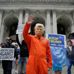 A person wearing an orange jumpsuit and a mask depicting U.S. President Donald Trump waves during the "No Kings Day" protest, in New York City, U.S., June 14, 2025. REUTERS/Eduardo Munoz