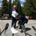 British Prime Minister Keir Starmer helps U.S. President Donald Trump pick up papers after Trump dropped the trade agreement with the U.K. as they speak to the media during the G7 summit in Kananaskis, Alberta, Canada, June 16, 2025. REUTERS/Kevin Lamarque