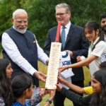 Britain's Prime Minister Keir Starmer looks on as Prime Minister Narendra Modi holds a Cricket bat, signed by Indian Cricket players, as they meet school children at Chequers near Aylesbury, England