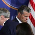 U.S. Treasury Secretary Scott Bessent stands next to U.S. Defense Secretary Pete Hegseth ahead of a joint press conference by U.S. President Donald Trump and Russian President Vladimir Putin, following their meeting to negotiate an end to the war in Ukraine, at Joint Base Elmendorf-Richardson in Anchorage, Alaska, U.S., August 15, 2025. REUTERS/Jeenah Moon