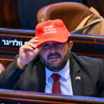 A man wearing a hat reading: "Trump The Peace President" sits inside the Knesset, on the day U.S. President Donald Trump delivers remarks, in Jerusalem, October 13, 2025. Kenny Holston/Pool via REUTERS