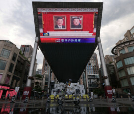 A woman rides a scooter past giant screen at a shopping area showing news footage of Chinese President Xi Jinping and North Korean leader Kim Jong Un attending a welcoming ceremony in North Korea, in Beijing, China, June 8, 2026. REUTERS/Tingshu Wang