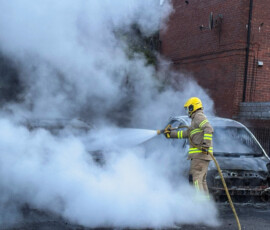 A firefighter works to extinguish a fire in three cars parked on the street at Tigers Bay, during a protest after a knife attack on June 8 left a man seriously injured and prompted police to declare a critical incident, in Belfast, Northern Ireland, June 9, 2026. REUTERS/Isabel Infantes