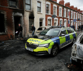 A police car drives past a burnt building on a debris-strewn street, in the aftermath of anti-immigrant protests following a knife attack on June 8, which left a man seriously injured and prompted police to declare a critical incident, at Lendrick Street, east Belfast, Northern Ireland, June 10, 2026. REUTERS/Isabel Infantes TPX IMAGES OF THE DAY