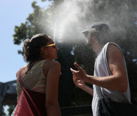 Two persons cool off at a water mister on a street in Paris as temperatures rise during a heatwave affecting a large part of France, June 22, 2026. REUTERS/Alice Sacco