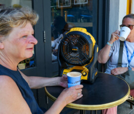 Friends Karen and Julie meet for a coffee with their DeWalt cordless portable fan before they start work, as Britain experiences record temperatures during a heatwave in Fulham, London, Britain, June 24, 2026. REUTERS/Kevin Coombs