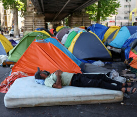 A migrant rests on a mattress near tents at a makeshift camp set up under an elevated railway of a Paris metro line near the Stalingrad subway station, as temperatures rise in paris during a heatwave affecting a large part of France, June 24, 2026. REUTERS/Abdul Saboor TPX IMAGES OF THE DAY