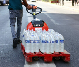 A man transports packs of water bottles on a wheeled pallet down a street as temperatures rise in Paris during a heatwave affecting a large part of France, June 24, 2026. REUTERS/Abdul Saboor