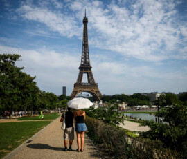 FILE PHOTO: People protect themselves from the sun under an umbrella near the Eiffel Tower as temperatures rise in Paris during a second heatwave affecting a large part of France, June 20, 2026. REUTERS/Sarah Meyssonnier/File Photo