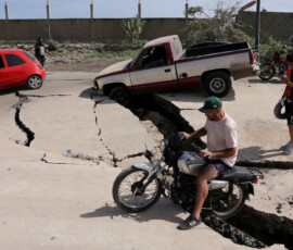 A man sits on a bike on a damaged road after earthquakes hit the country, in La Guaira, Venezuela, June 25, 2026. REUTERS/Gaby Oraa TPX IMAGES OF THE DAY