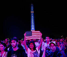 A woman holds up a U.S. flag at a Fourth of July rally featuring U.S. President Donald Trump, marking the 250th anniversary of U.S. independence, on the National Mall in Washington, D.C., U.S., July 4, 2026. REUTERS/Evan Vucci